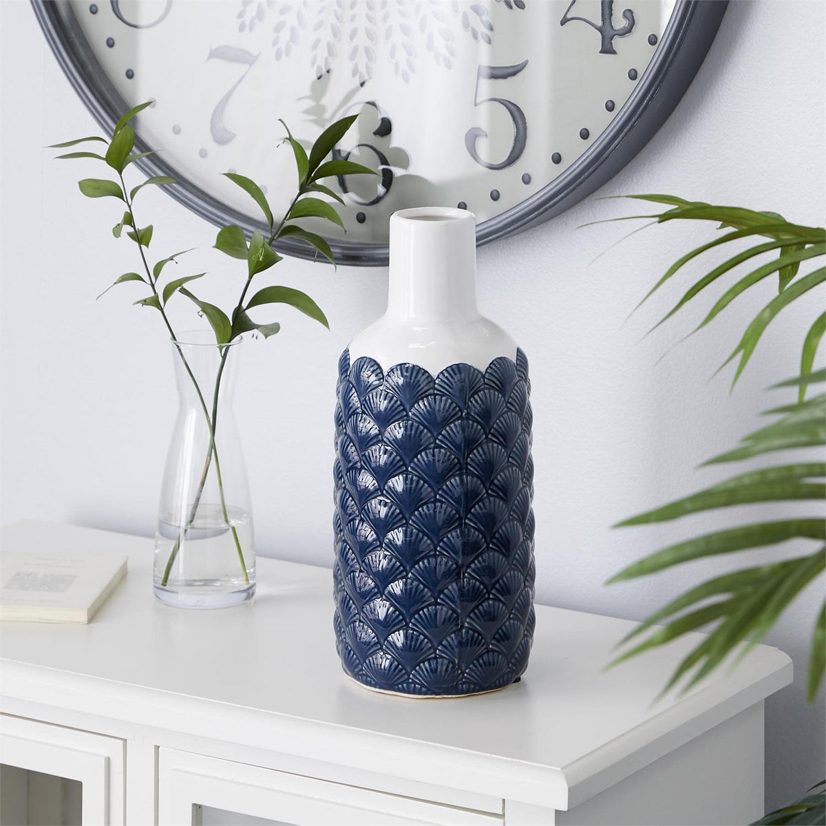 Blue and white ceramic vase with raised shell patterns on a styled console